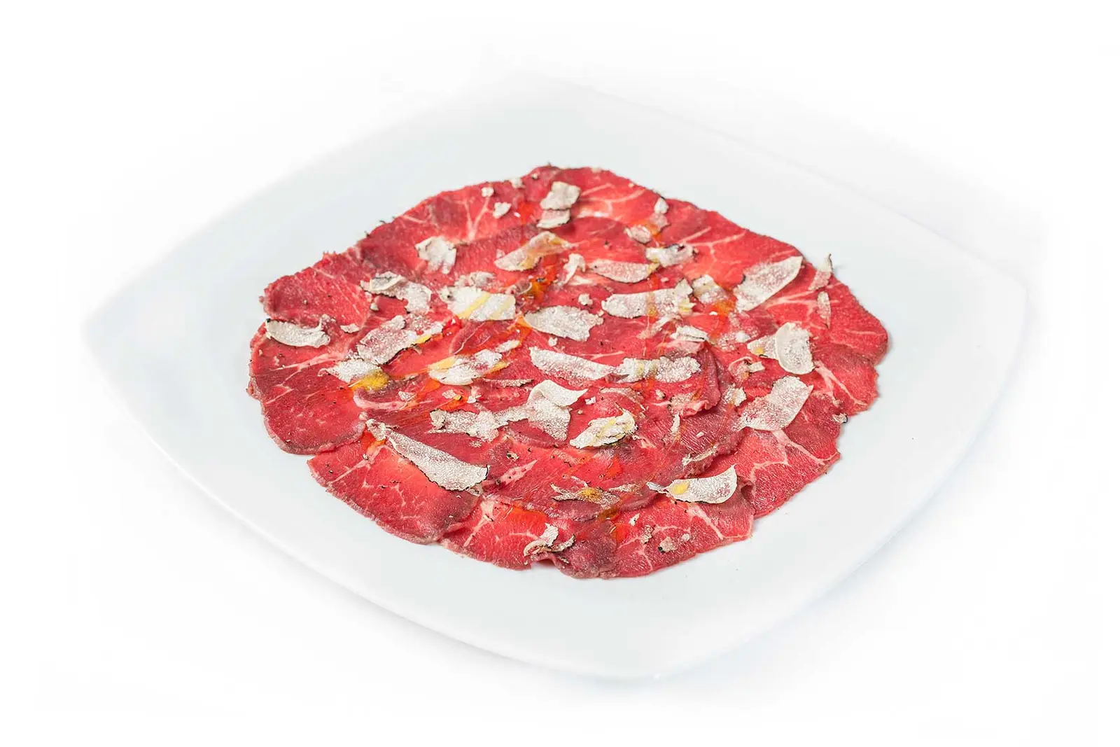 Carpaccio: hauchdünne Rinderfiletscheiben mit Parmesan auf weißem Teller.