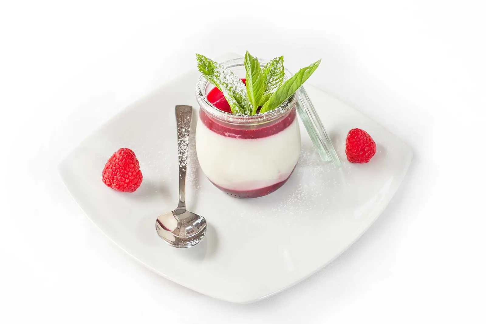 Panna cotta im Glas mit Himbeeren und Minze.